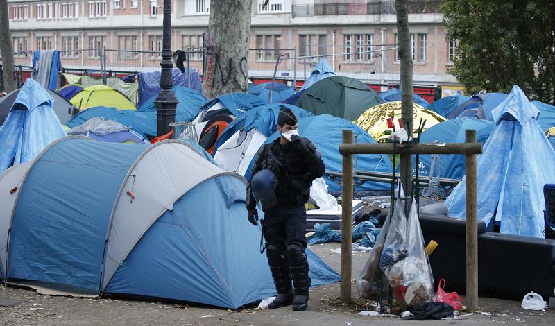 Un agent de police anti-émeute surveille les tentes d'un campement pour migrants près de la station de métro Stalingrad, à Paris, le 4 novembre 2016, date à laquelle ce campement provisoire a été démantelé.