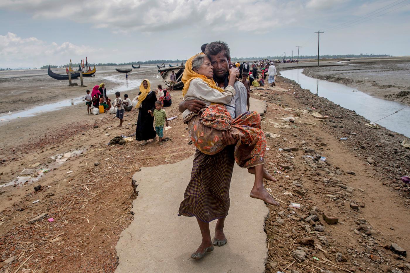 Abdul Kareem, a Rohingya Muslim, carries his mother, Alima Khatoon, to a refugee camp after crossing from Burma into Bangladesh on Sept. 16, 2017.