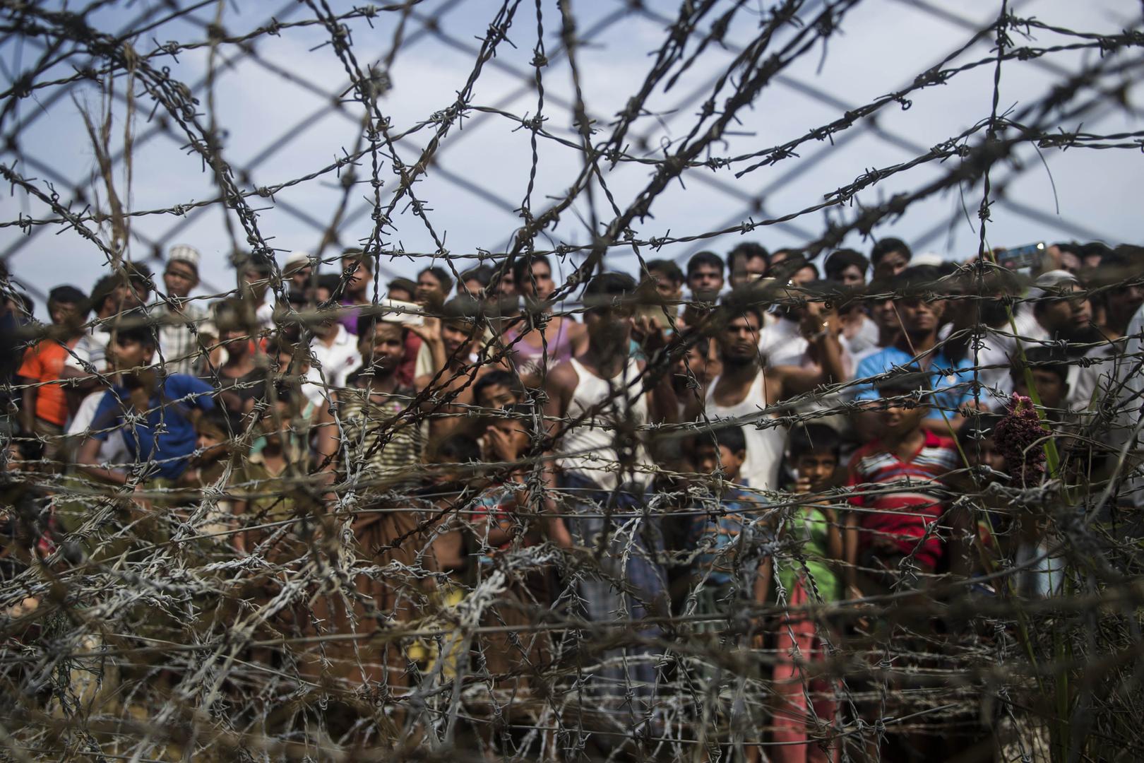 Rohingya refugees gather behind a barbed-wire fence in the “no-man’s land” border zone between Myanmar and Bangladesh, April 25, 2018.