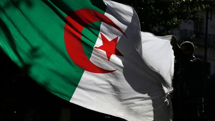 An Algerian demonstrator holds the Algerian national flag as he stage a protest against the government in Algiers, Algeria, Friday, Nov.29, 2019. 