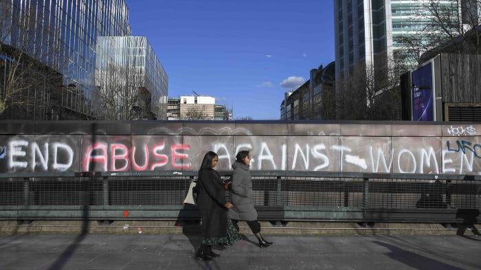 People walk past a graffiti reading ‘End abuse against women’ on Euston Road, in London, Friday March 6, 2020.