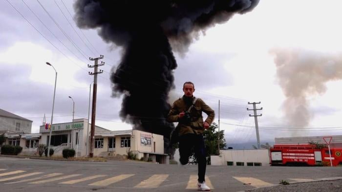 Man running from impact zone of explosive weapon in Nagorno-Karabakh