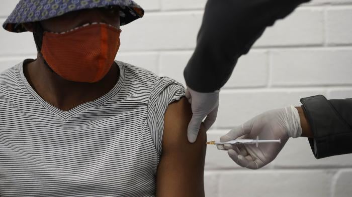 A man wearing a mask receives a vaccination in the arm