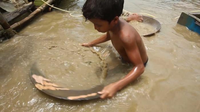 Child sifting for minerals in river