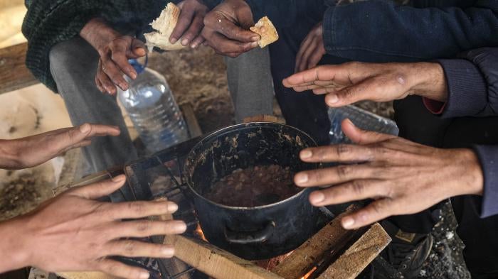 Migrants warm their hands above a fire at the Lipa camp, outside Bihac, Bosnia and Herzegovina, Monday, January 11, 2021. The camp was closed on December 23, 2020 and destroyed in a fire the same day. 