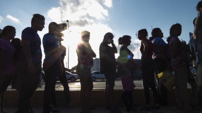 Migrants seeking asylum wait in line with their case paperwork to meet with an attorney on Oct. 5, 2019, during a weekly trip by volunteers, lawyers, paralegals and interpreters to the migrant campsite outside El Puente Nuevo in Matamoros, Mexico.