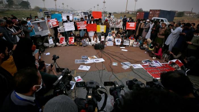 People hold placards and portraits of their missing family members during a press conference in Islamabad, Pakistan, February 20, 2021. 