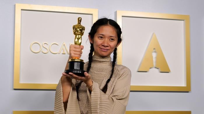 Director Chloe Zhao smiles and holds her golden Oscars statue after winning the award for Best Director