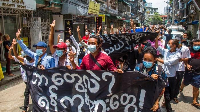 Anti-coup protesters hold a banner that reads "What are these? We are Yangon residents!" as they march during a demonstration in Yangon, Myanmar on Tuesday April 27, 2021.