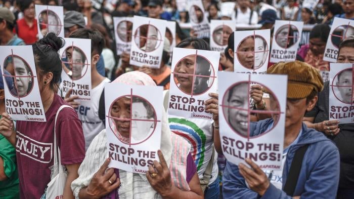 Protesters hold up pictures of victims of extrajudicial killings during Human Rights Day protests in Manila