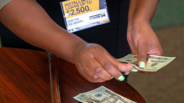 A manager of a financial services counts cash being paid to a client as part of a loan in Ballwin, Missouri on August 9, 2018