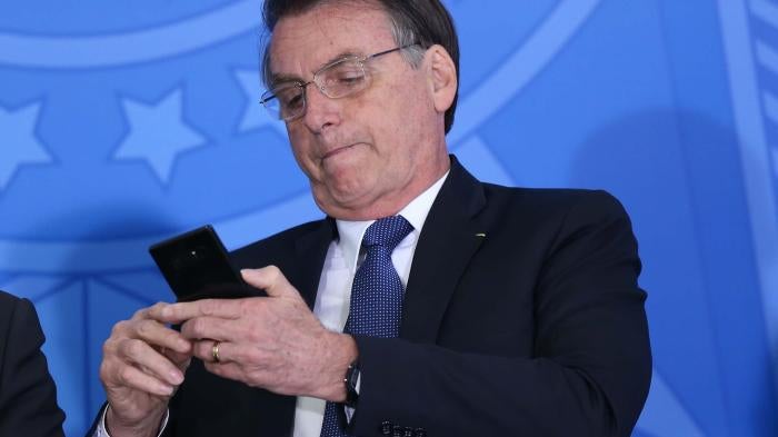 Brazil’s President Jair Bolsonaro uses his cellphone during at event at the presidential palace in Brasilia on June 13, 2019. 