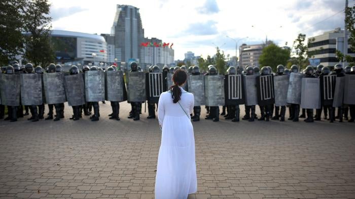 A woman wearing white stands in front of riot police during a Belarusian opposition rally protesting the official presidential election results in Minsk, Belarus, September 13, 2020. 