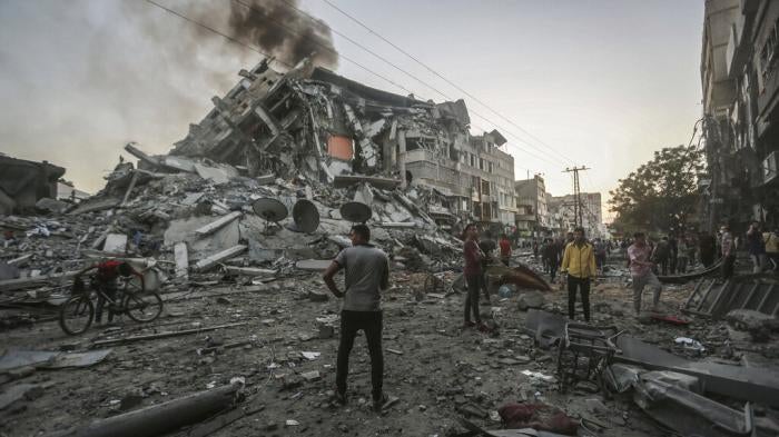 People in the Gaza Strip stand near the site of the collapsed al-Shorouk tower