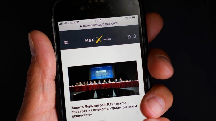 A smart phone user reads MBKh Media news site, one of three news outlets whose websites were blocked on August 4, 2021.