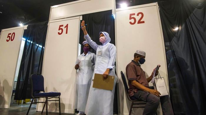 A health worker gestures to the next vaccine recipient at Malaysia International Trade & Exhibition Centre in Kuala Lumpur, Malaysia on May 31, 2021.
