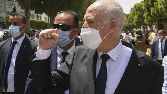 Tunisian President Kais Saied raises his fist to bystanders as he walks along the avenue Bourguiba in Tunis, Tunisia, August 1, 2021.