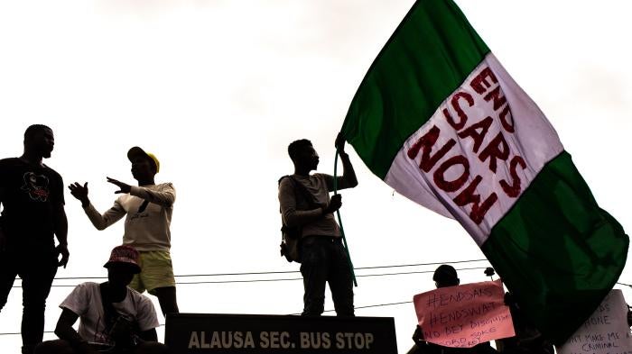 #EndSARS protesters hold up signs, including a Nigerian flag with a message calling for the disbandment of the abusive police unit, during protests on October 15, 2020 in Alausa Lagos, Nigeria. 