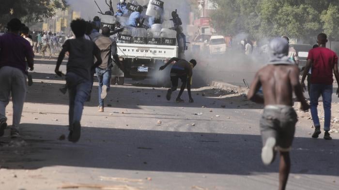 Men run towards an armored police vehicle