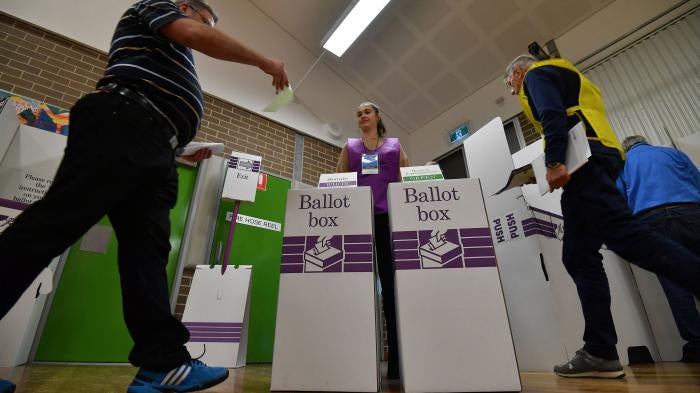 A voter drops his ballot paper into the ballot box during Australia's general election in Sydney.