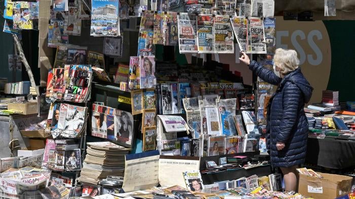 A woman reads newspaper's headlines referring to the killing of a Greek journalist in Athens on April 10, 2021.