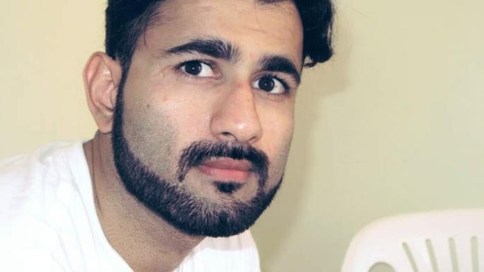 Photo of a man with black hair and a bear