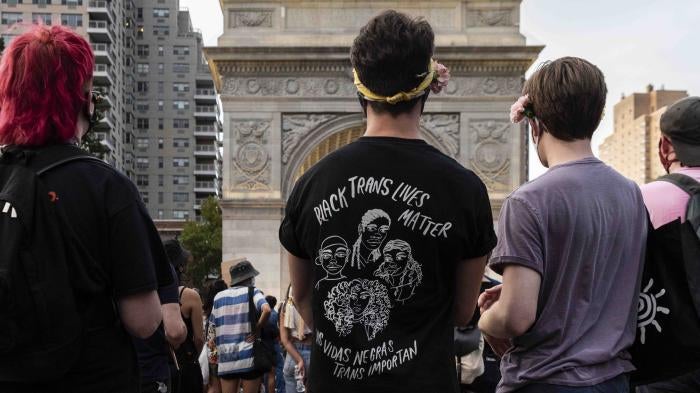 A person wearing a shirt that says "Black Trans Lives Matter (Las vidas negras trans importan)" at a rally