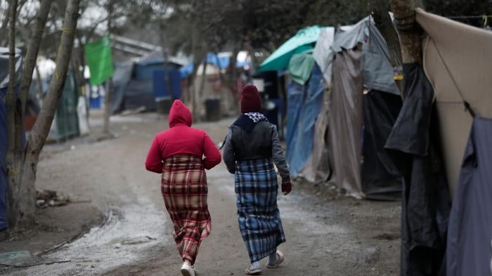 Migrant women walk inside a migrant encampment in Matamoros, Mexico, February 18, 2021.