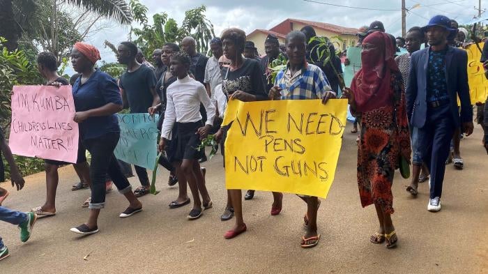 A group of protesters holding signs that say "We Need Pens, Not Guns"
