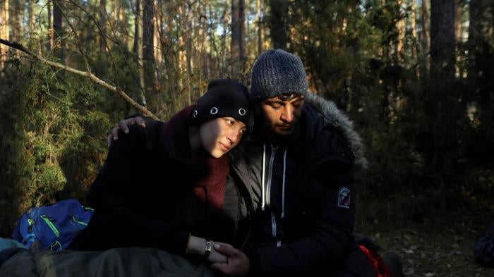 Sara, 26, and Hassan, 24, both from Syria, sit on the ground in the forest in Lewosze, Poland, after crossing the border from Belarus, October 29, 2021.