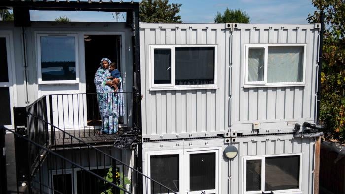 A mother stands with her son outside the front door to their accommodation at a development of converted shipping containers