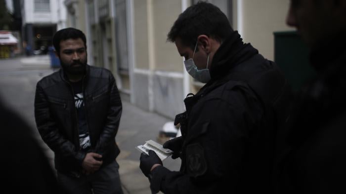Police officers check the documents and permissions of people in the streets of Athens, Greece, March 23, 2020. 