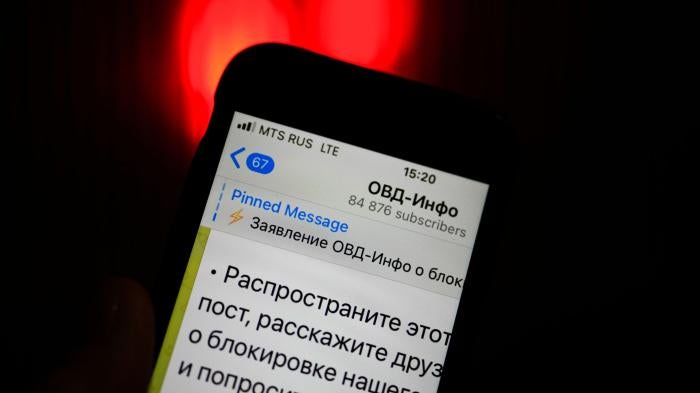 An iPhone screen shows the Telegram account of OVD-Info