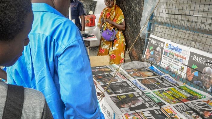 People stop to read front pages at a newspaper stand on a street in Dar es Salaam, Tanzania, March 18, 2021.