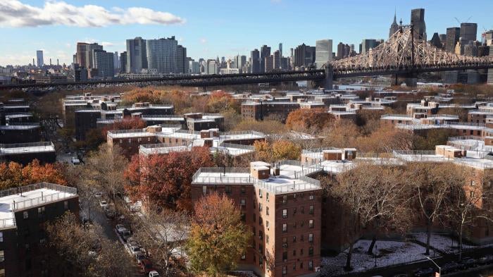 Aerial view of a housing complex with a city skyline behind it