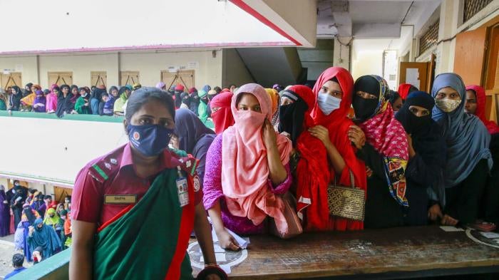 Women in protective face masks stand in a long line