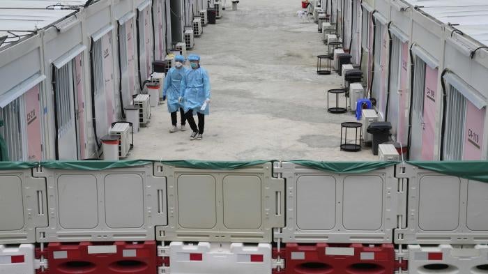 Healthcare workers walk along the makeshift Covid-19 isolation facilities in the San Tin area of Hong Kong, March 11, 2022. 
