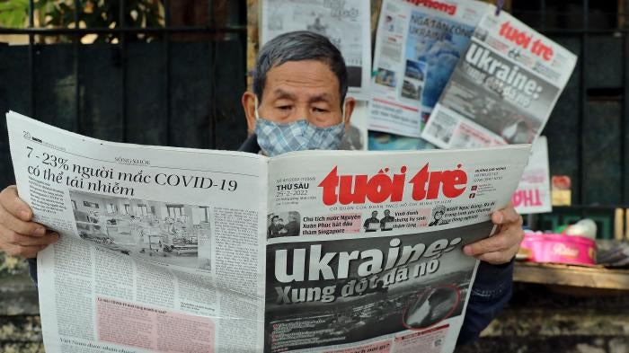 A man reads a Vietnamese newspaper featuring frontpage coverage of the Russian invasion of Ukraine at a stall in Hanoi on February 25, 2022.