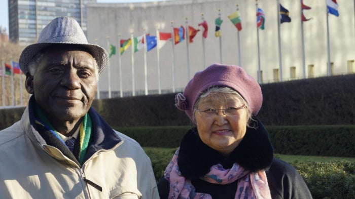 A man and woman pose in front of the United Nations