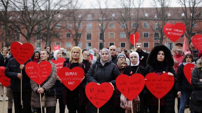 Protesters hold red heart-shaped signs