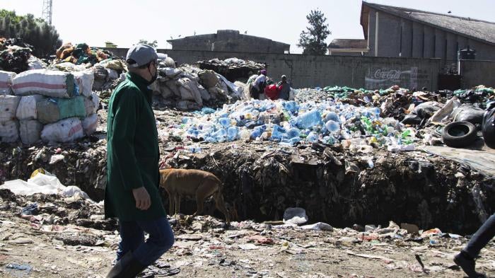 A man walks by a mound of plastic waste