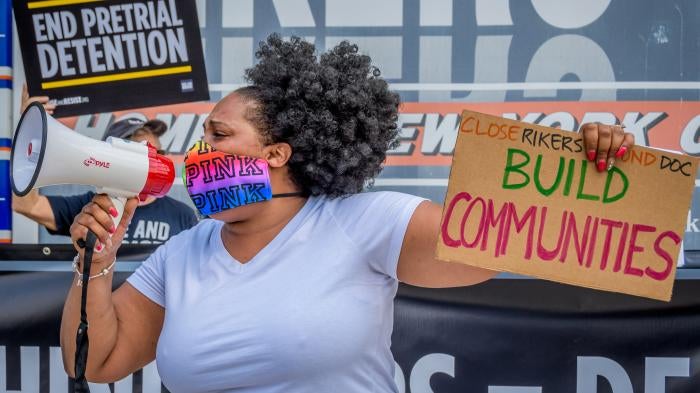 A participant holds a “Build Communities” sign at a rally on Rikers Island in New York, NY. 