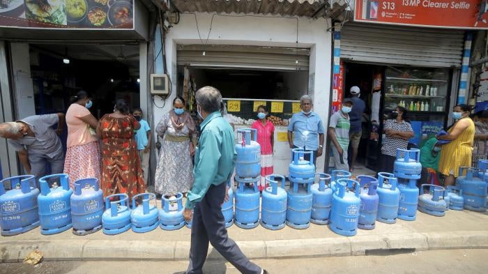 Sri Lankans wearing facemasks wait in line with their empty gas cylinders near a gas shop at Colombo, Sri Lanka, April 1, 2022.
