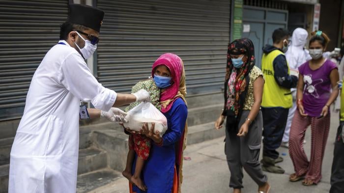A woman and her child receive relief goods distributed by a community service center in Kathmandu, Nepal on June 4, 2021. 