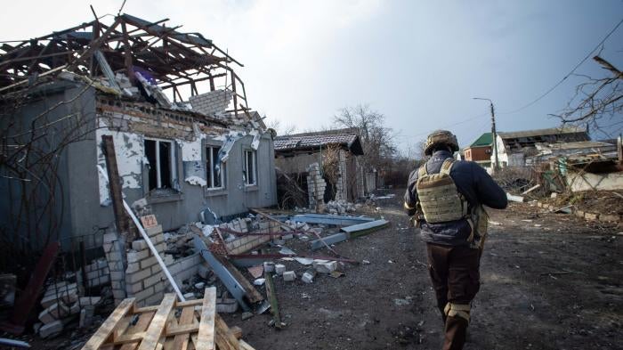 A member of the Ukrainian armed forces walks past the wreckage of a house damaged by rockets on the southern outskirts of Mykolaiv, Ukraine on March 9, 2022. © 2022 Scott Peterson/Getty Images