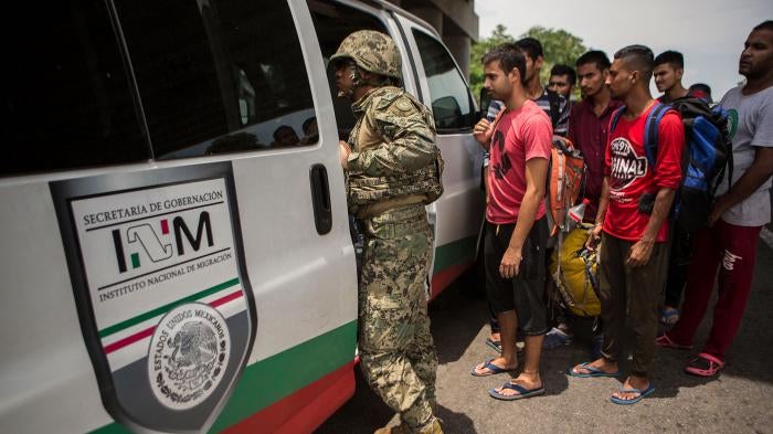 A Mexican Marine orders a group of migrants from Bangladesh, India and Pakistan off a bus at an immigration checkpoint