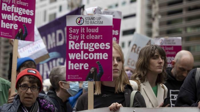 Protesters hold placards reading "refugees welcome here" at a demonstration