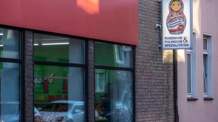 A smashed window pane and smeared white paint are seen on a Russian-Polish supermarket