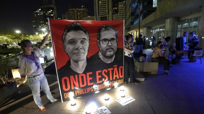 People display a large poster with images of Dom Phillips and Bruno Pereira