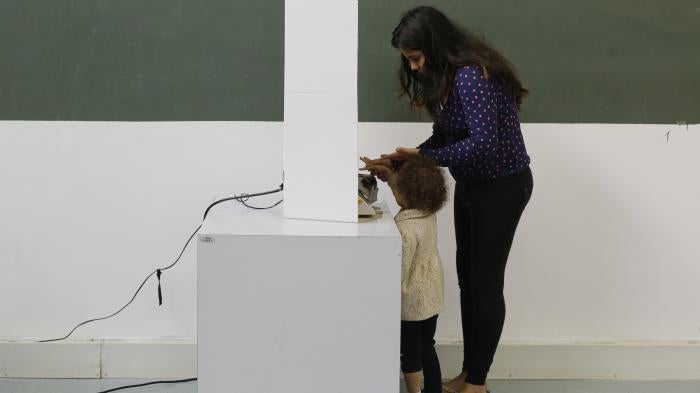 A woman, accompanied by a child, casts her ballot in the municipal election in Sao Paulo, Brazil, Sunday, Oct. 2, 2016.
